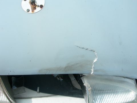 1984 Ford Bronco - A scratch mars the hood of a vehicle, with a broken headlight visible underneath.