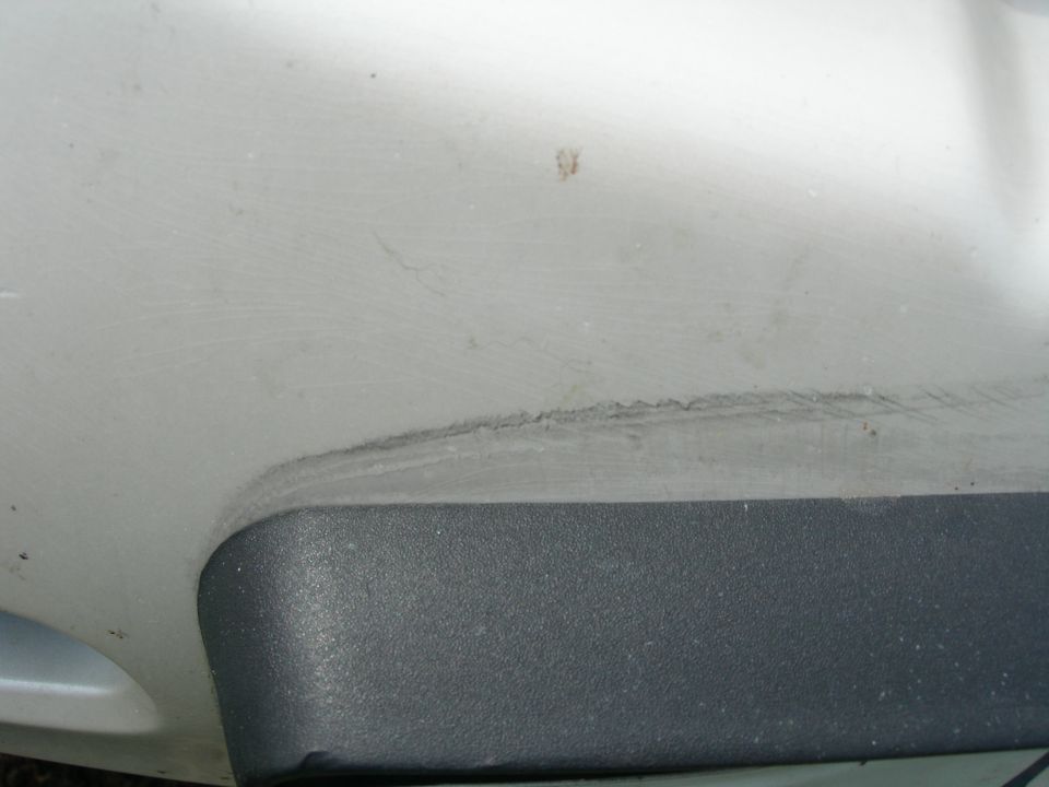 White car body panel with scuff marks above black textured trim