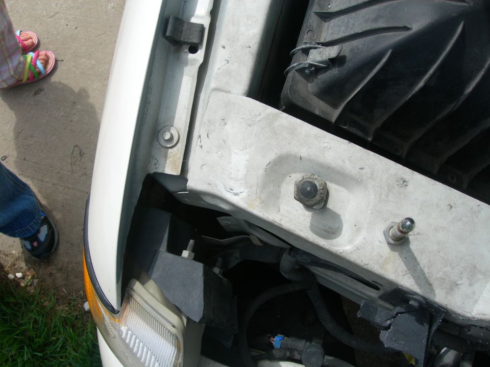 Close-up of car engine bay with headlight visible on the left
