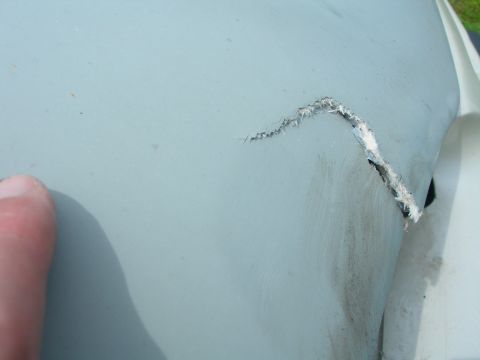 1984 Ford Bronco - A damaged section of a vehicle's exterior panel is shown, with a tear exposing the material beneath.