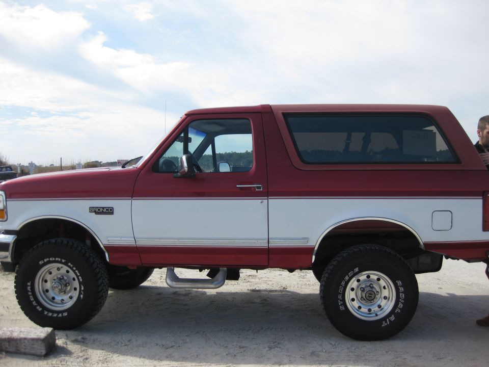1995 Ford Bronco, two-tone red and white, side view. "BRONCO" badge visible on fender