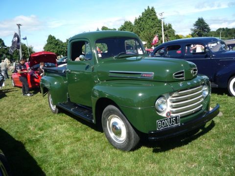 1969 Lincoln Continental - This green 1948 Ford F1 pickup truck is parked on grass at an outdoor event.