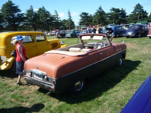 1969 Lincoln Continental - A two-tone convertible is parked on a grassy field with other vehicles and trees in the background.