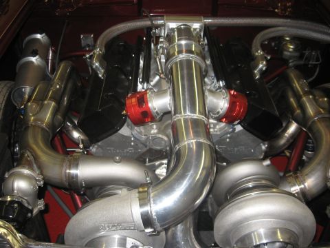 1965 Ford Fairlane - Close-up view of a custom twin-turbocharged V8 engine, polished intake piping and red blow-off valves.