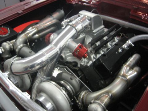 1965 Ford Fairlane - Close-up view of a custom twin-turbocharged V8 engine with extensive polished metal piping.