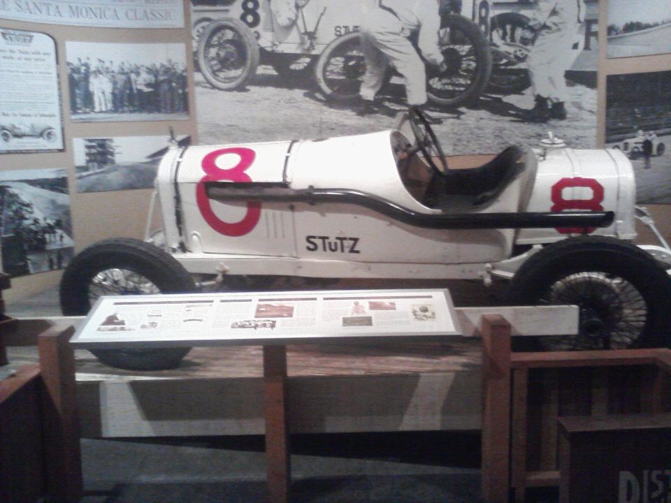 White race car with red number 8 and STUTZ text on its side, displayed in a museum