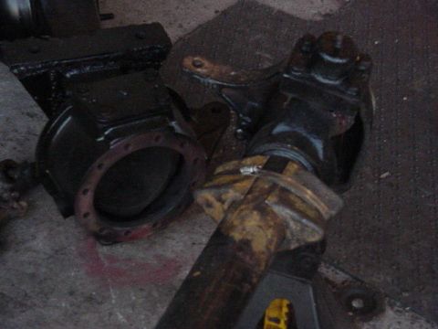 1992 Ford Bronco - Vehicle axle components, including a differential housing and driveshaft, are shown on a concrete surface.