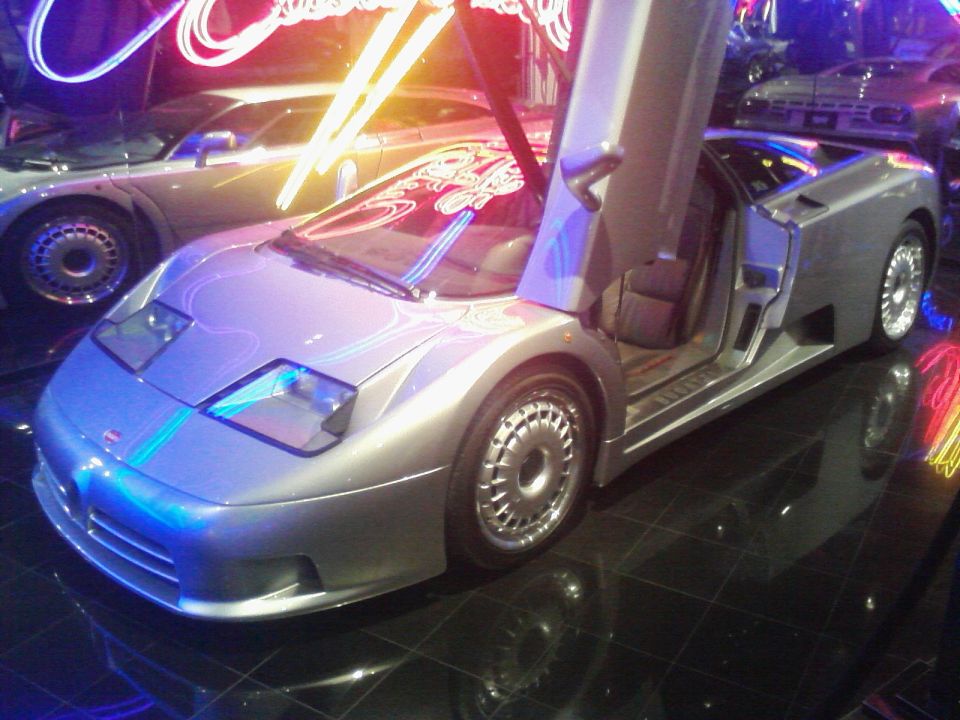 Silver Bugatti EB110 with doors open, showing interior and distinctive wheels