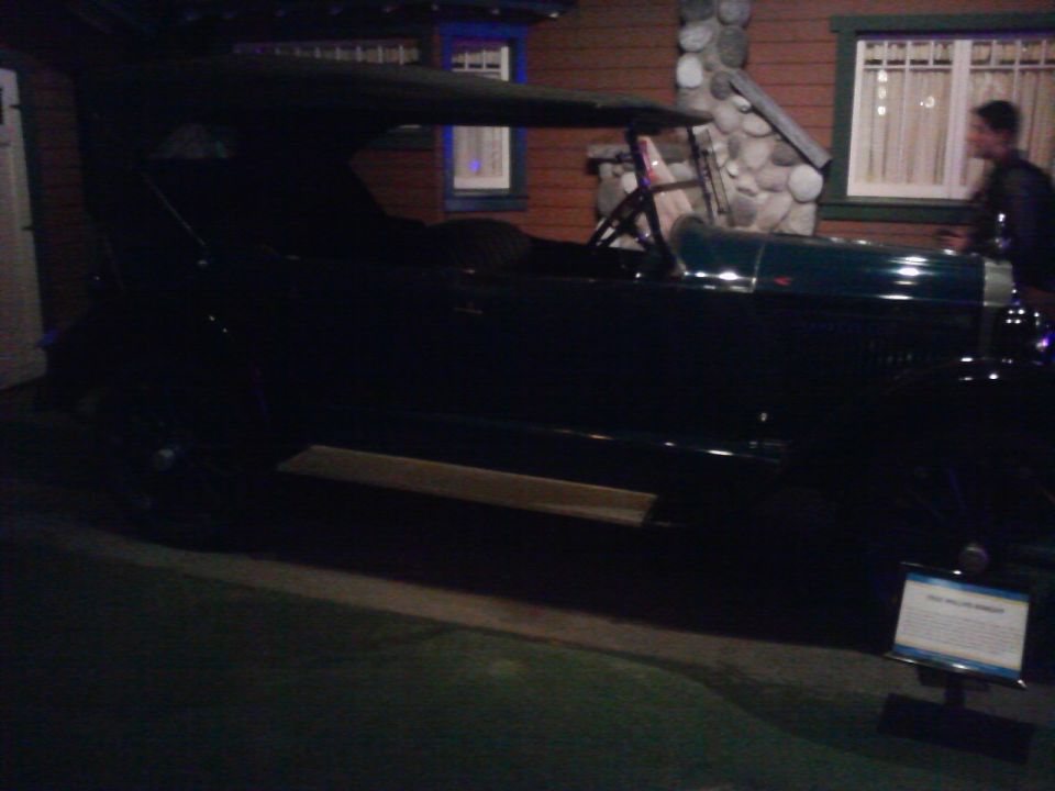 Antique car with a dark body and a tan running board, parked indoors