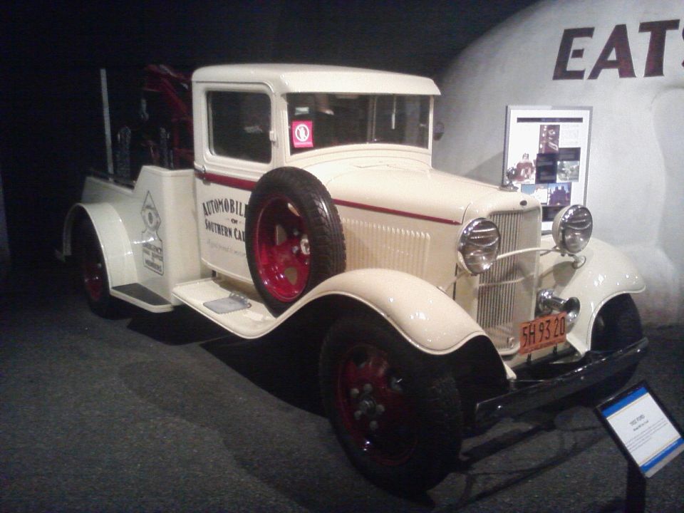 Cream-colored tow truck with red trim and a spare tire on the side