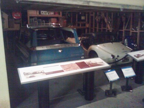 1995 Ford Taurus - Two classic cars are displayed indoors, with informational displays in front of them.
