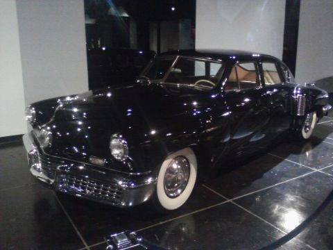 1995 Ford Taurus - A classic black sedan with a distinctive grille and whitewall tires is displayed indoors.