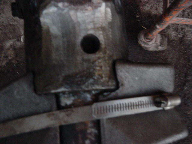 Close-up of a metal bracket with a hose clamp attached. Supermotors.net logo visible
