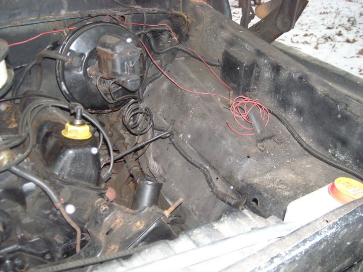 Engine bay with brake booster, master cylinder, and wiring. Some rust and dirt visible