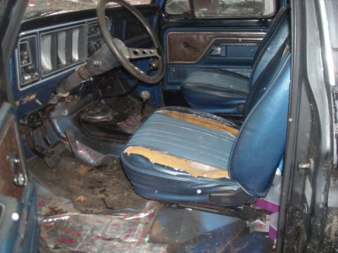 1979 Ford Bronco - The interior of the vehicle shows worn blue seats and a floor-mounted shifter.