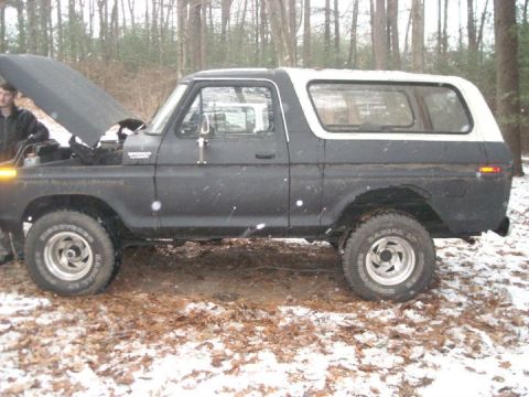 1979 Ford Bronco - A 1979 Ford Bronco sits in a wooded area with its hood open, showing some snow on the ground.
