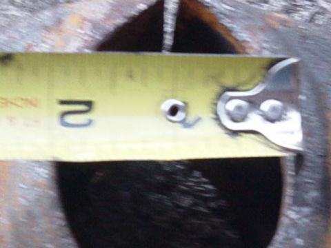 1992 Ford Bronco - Measuring a component with a yellow tape measure. The surface is dark and rough.