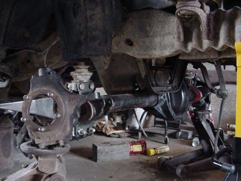 1992 Ford Bronco - Close-up of a vehicle's front axle assembly, supported by jack stands, with a visible part number.
