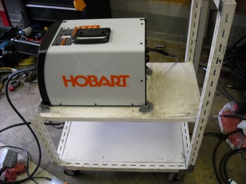 1979 Ford F-150 - A Hobart welding machine sits on a two-tiered metal cart in a workshop setting.