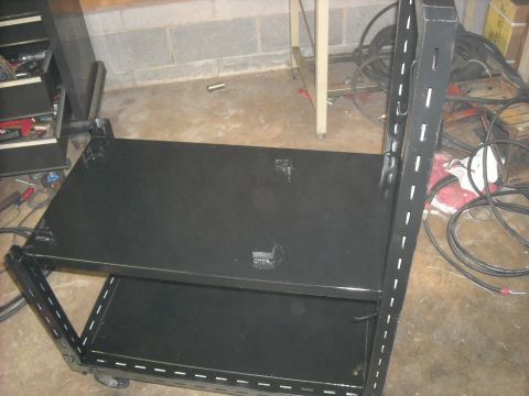 1979 Ford F-150 - A black rolling tool cart with two shelves is shown in a garage setting.