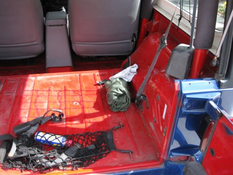 1998 Jeep Wrangler - The interior of a Jeep Wrangler shows the rear cargo area with items stored in a net and on the floor.