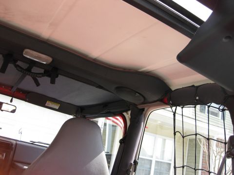1998 Jeep Wrangler - The interior of a Jeep shows speakers mounted above the doors and a sun visor with a warning label.