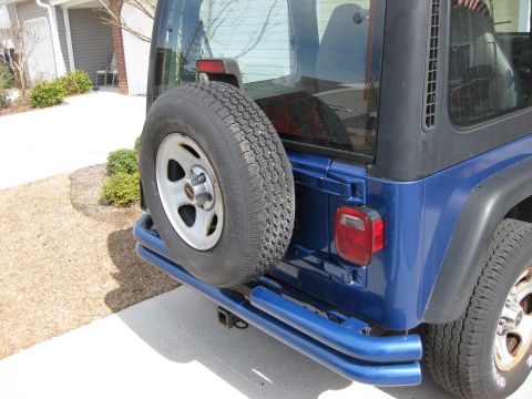 1998 Jeep Wrangler - Rear view of a blue Jeep Wrangler showing the spare tire and custom bumper.