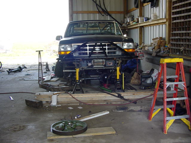 Black 1992 Ford Bronco front end on jack stands in a garage