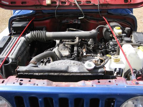 1998 Jeep Wrangler - The engine bay of a Jeep Wrangler is visible with the hood raised.