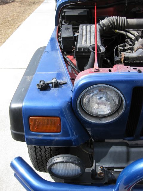 1998 Jeep Wrangler - Close-up of a blue Jeep Wrangler's front end, revealing the engine bay and headlight assembly.