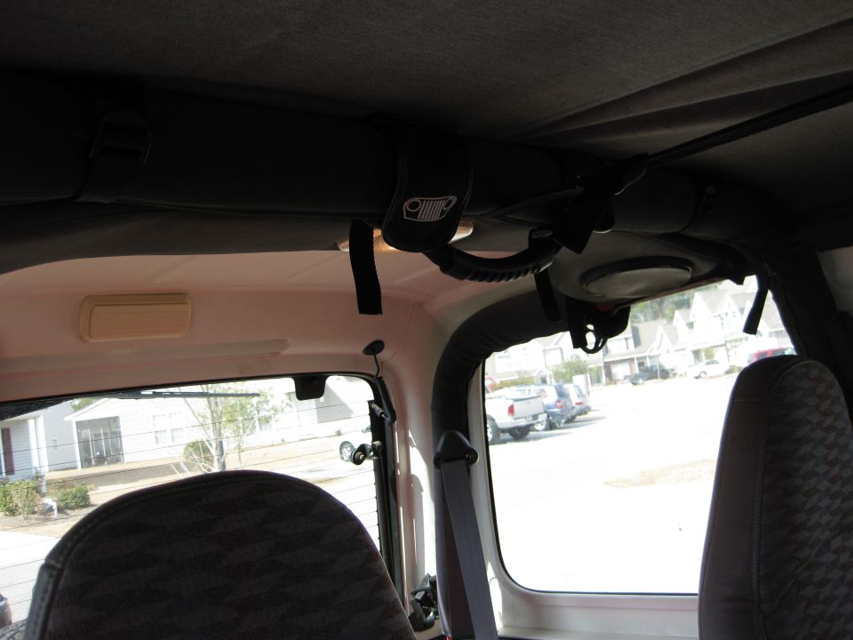 Jeep interior showing grab handle with Jeep logo, overhead console, and rear seat