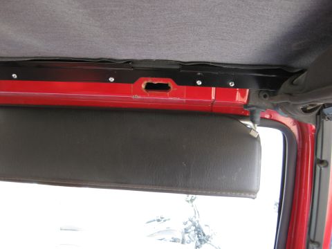 1998 Jeep Wrangler - Close-up of the interior of a red Jeep, focusing on the sun visor and headliner area.