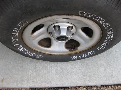 1998 Jeep Wrangler - This image shows a close-up of a tire and wheel assembly, clearly marked as a Jeep Wrangler.