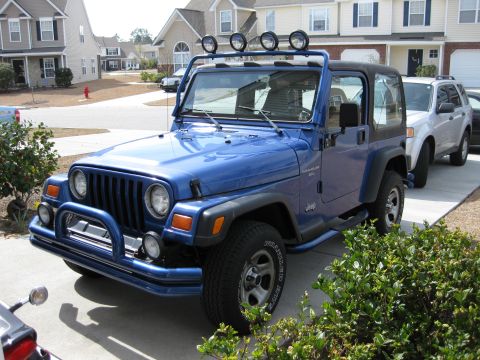 1998 Jeep Wrangler - Blue Jeep Wrangler TJ model parked in a suburban driveway with a silver SUV behind it.
