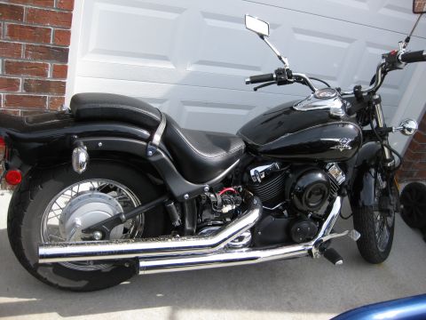1998 Jeep Wrangler - A black motorcycle is parked in front of a garage door, with a brick wall to the left.