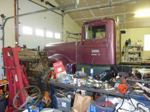 1971 Ford Mustang - A maroon truck cab and its engine are visible in a cluttered garage, surrounded by tools and various parts.