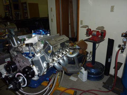 1971 Ford Mustang - A custom V8 engine is shown on an engine stand, surrounded by garage equipment and parts.
