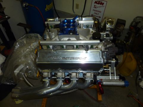 1971 Ford Mustang - A Ford Motorsport engine with chrome valve covers and a blue intake is displayed on a stand.