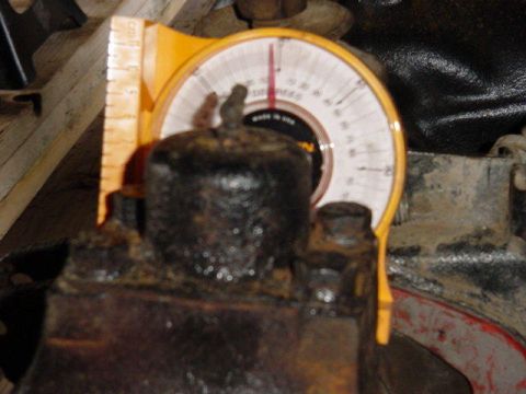 1992 Ford Bronco - yellow magnetic protractor angle gauge with degree scale placed on an oily cast-iron engine block, reading made in USA.