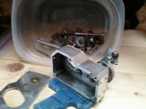 1996 Ford Bronco - A close-up view of disassembled mechanical parts, including gears and a metal housing, resting on a wooden surface.