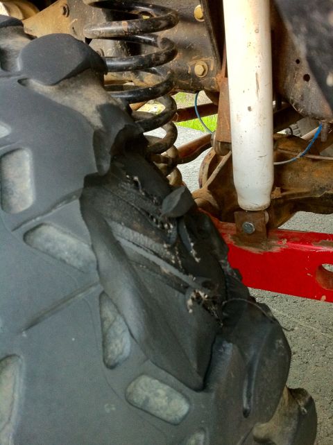 1989 Ford Bronco - Close-up view of a severely damaged off-road tire, revealing its internal structure and surrounding suspension parts.