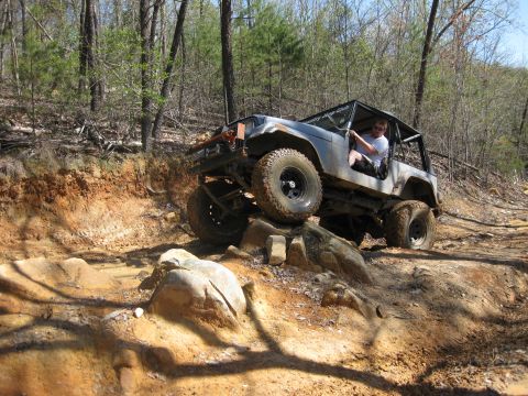 1998 Jeep Wrangler - A modified Jeep navigates a challenging rocky terrain on an off-road trail.