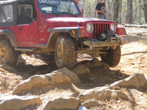 1998 Jeep Wrangler - A red Jeep Wrangler navigates a challenging rocky obstacle course.