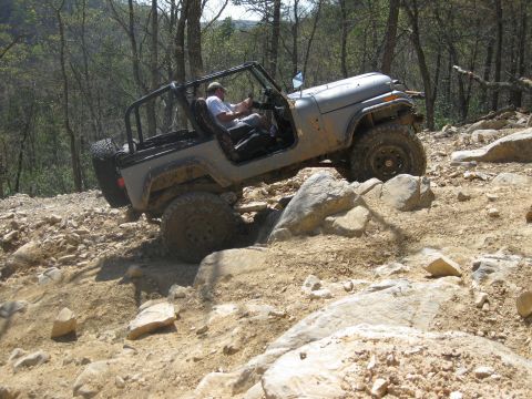 1998 Jeep Wrangler - A gray 1998 Jeep Wrangler tackles a challenging rocky trail, demonstrating its off-road capabilities.