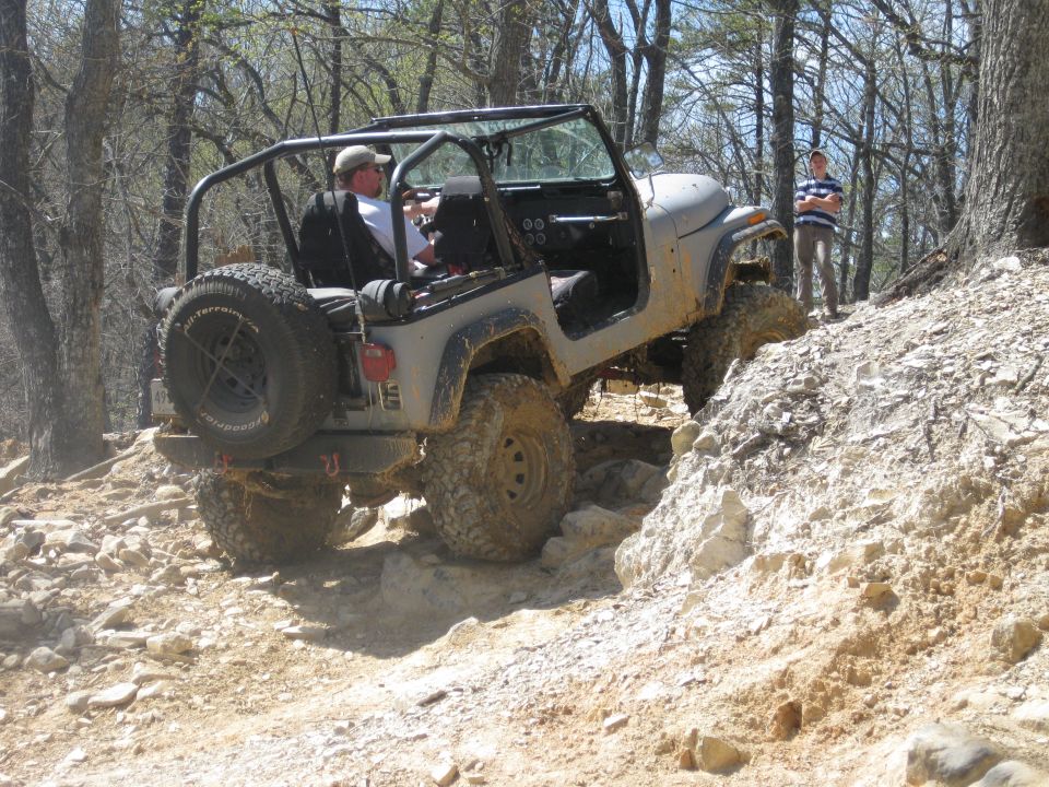 1998 Jeep Wrangler climbing a steep, rocky trail with trees on either side