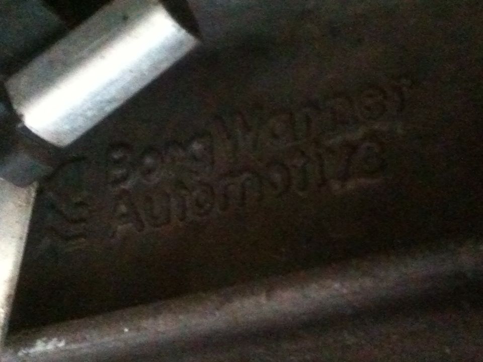 Cast metal part with embossed text 'Borg Warner Automotive'