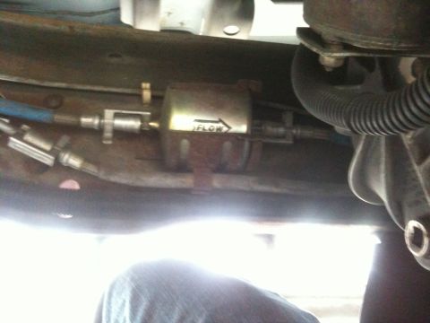 1995 Ford Bronco - Close-up of a vehicle's fuel filter, showing the direction of flow.