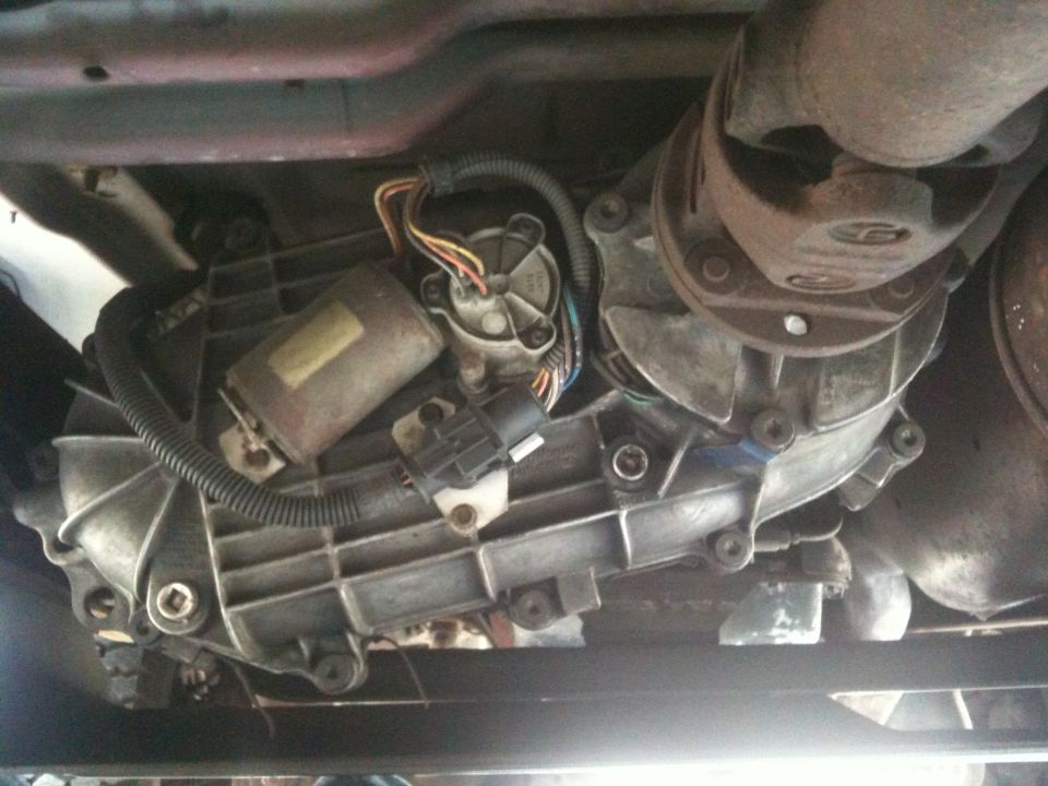 Underside view of a vehicle's transfer case, driveshaft, and related components
