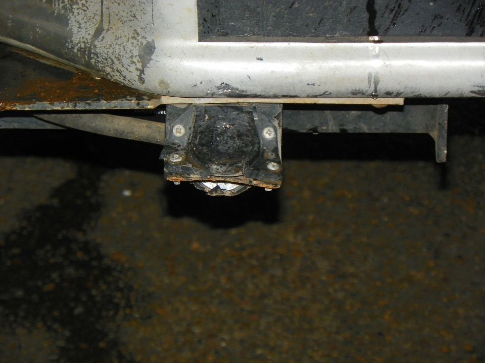 Trailer hitch wiring connector mounted to vehicle frame. Shows rust and wear