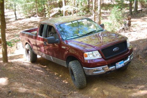 2005 Ford F-150 - Maroon 2005 Ford F-150 pickup truck navigating a wooded dirt path.